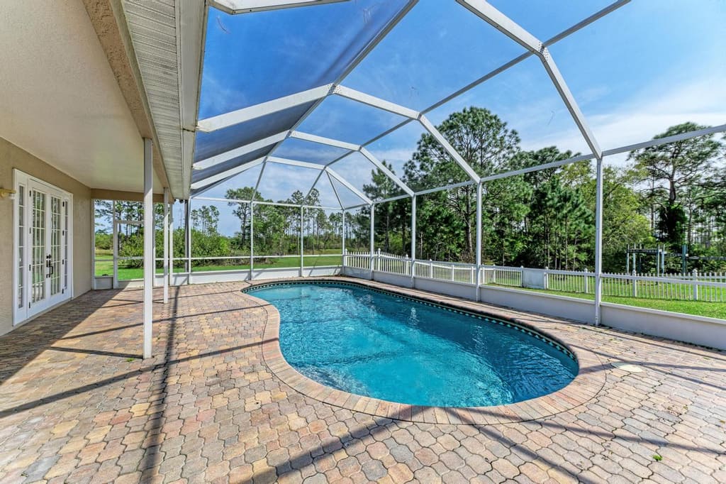 Screened pool, sunny patio and wooded backyard at 21616 67th Ave E in Panther Ridge